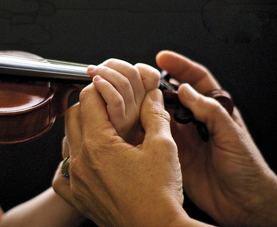 Teacher correcting student hand position on violin