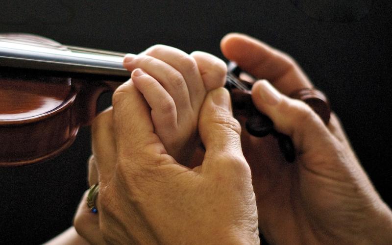 Teacher correcting student hand position on violin